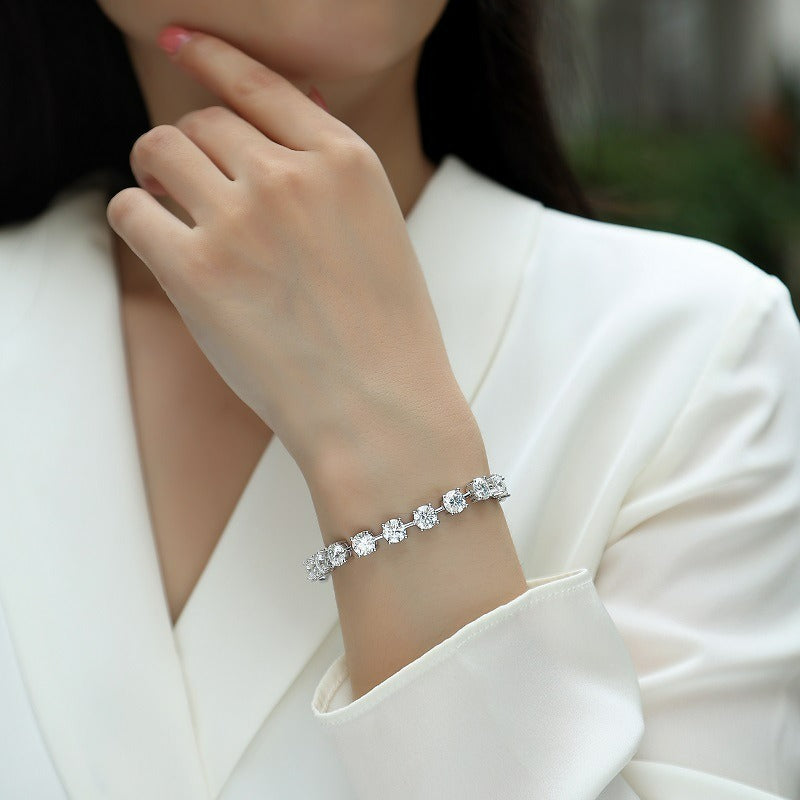 Close-up of a person wearing a silver bracelet with clear stones on a blurred background
