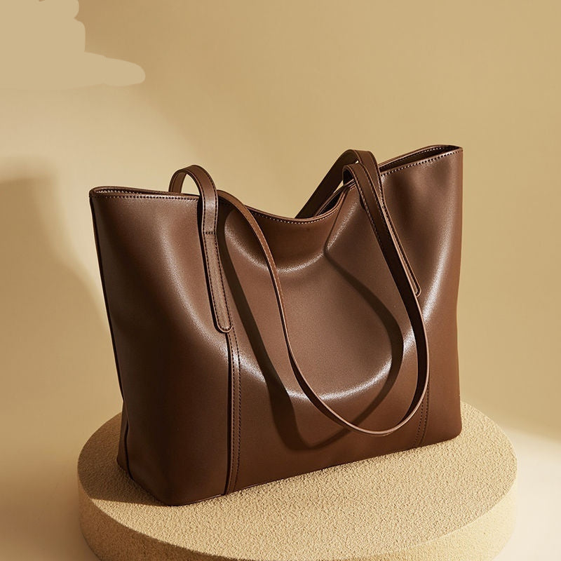 Brown leather tote bag on a beige background